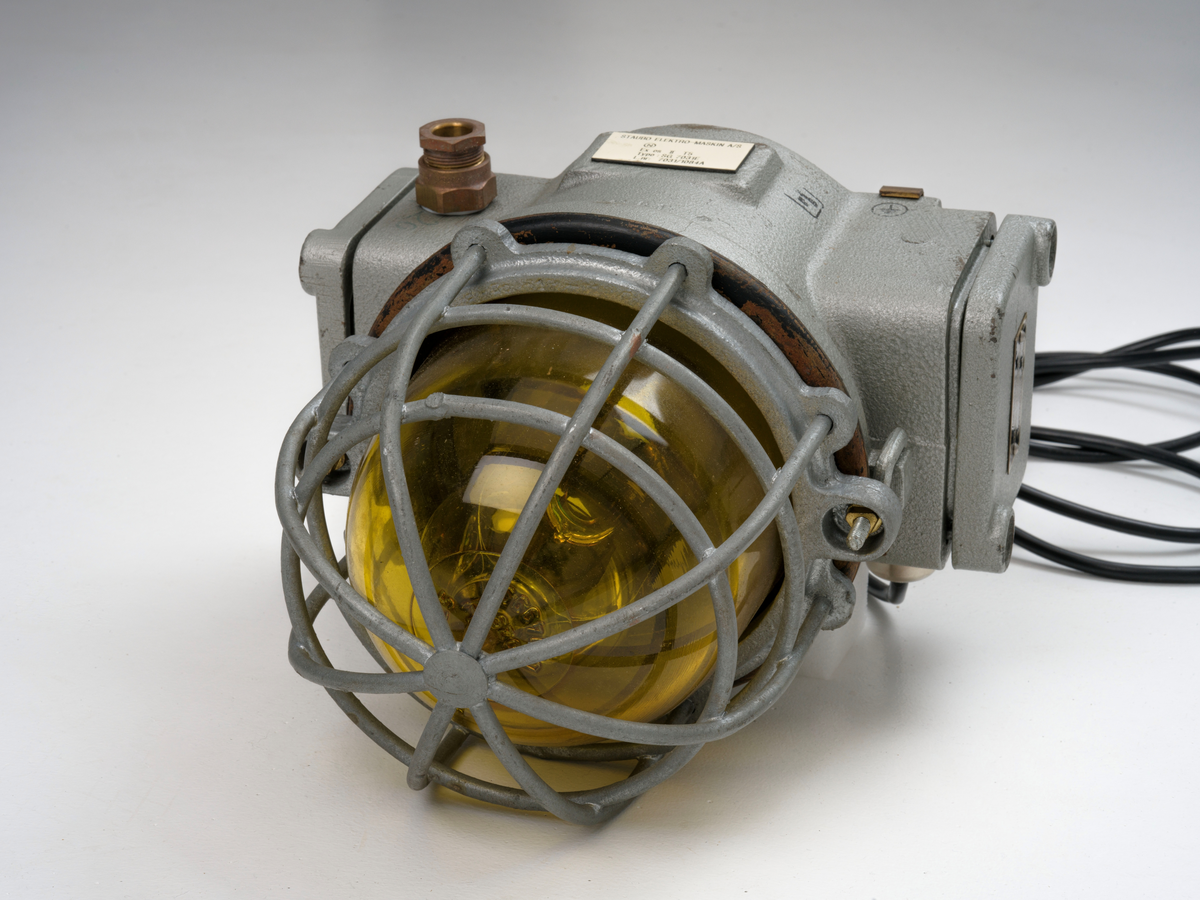 Signallampe med kuppel av glass og to avtagbare deksler som er festet med skruer.