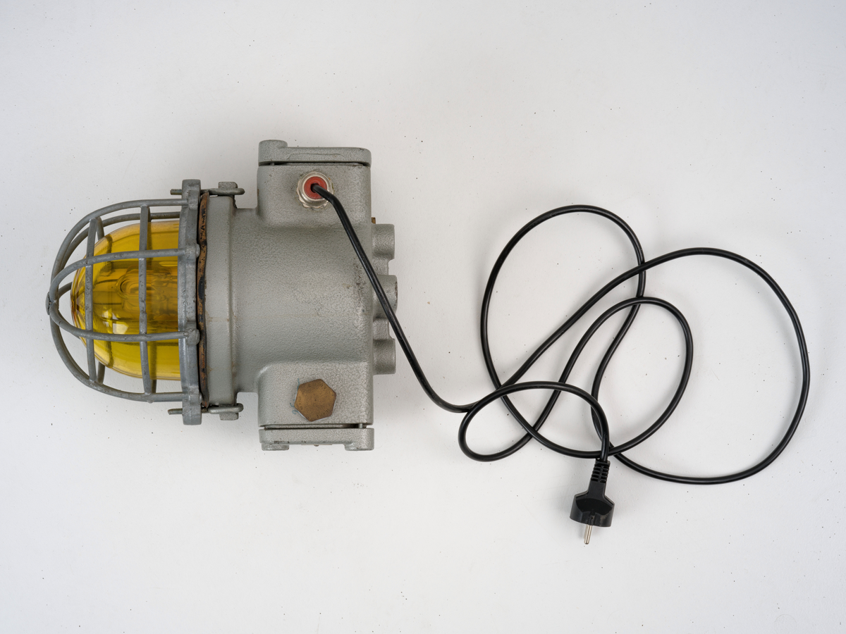 Signallampe med kuppel av glass og to avtagbare deksler som er festet med skruer.