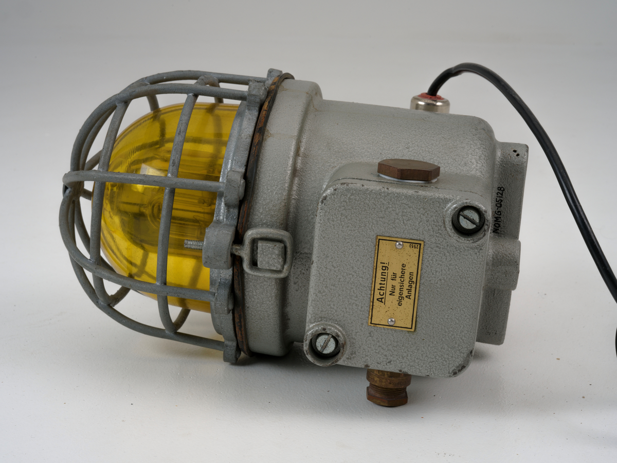 Signallampe med kuppel av glass og to avtagbare deksler som er festet med skruer.