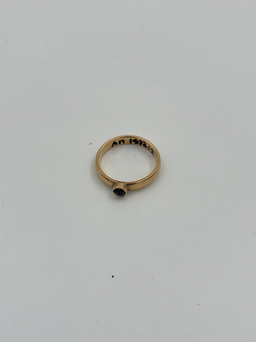 Guldring med granat.

Stämplar: 
Mästarstämpel: LEL = Ludvig Edvard Liljeblad
20K = 20 karat
Kattfot
Ortsstämpel: A = Alingsås
Årsbokstav X5 = 1876