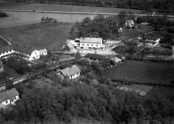 Flygbild över Kärradal med affären och Turisthotellet. Enfamiljshus och trädgårdar. Träd och odlingslandskap.