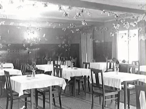 Interiör. Matsalen på Solbackens pensionat i Kärradal. Rummet är dekorerat med blomkvistar.