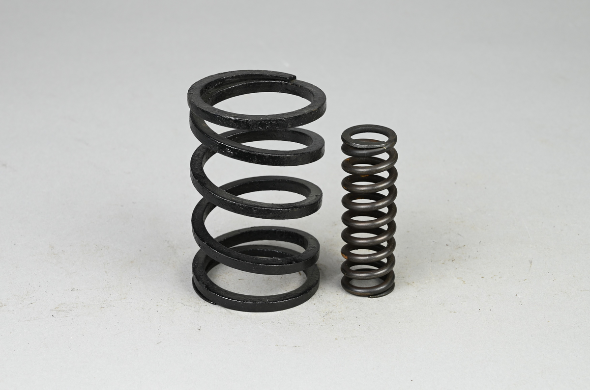 Två prov på diverse spiralfjädrar, svart. Tillverkad av A-B. Spiralfabriken. Tillhörande lapp med samma notering.