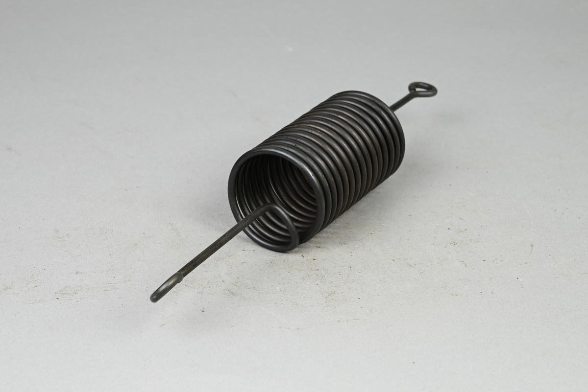 Prov på spiralfjäder, svart. Tillverkad av A-B. Spiralfabriken. Tillhörande lapp med samma notering.