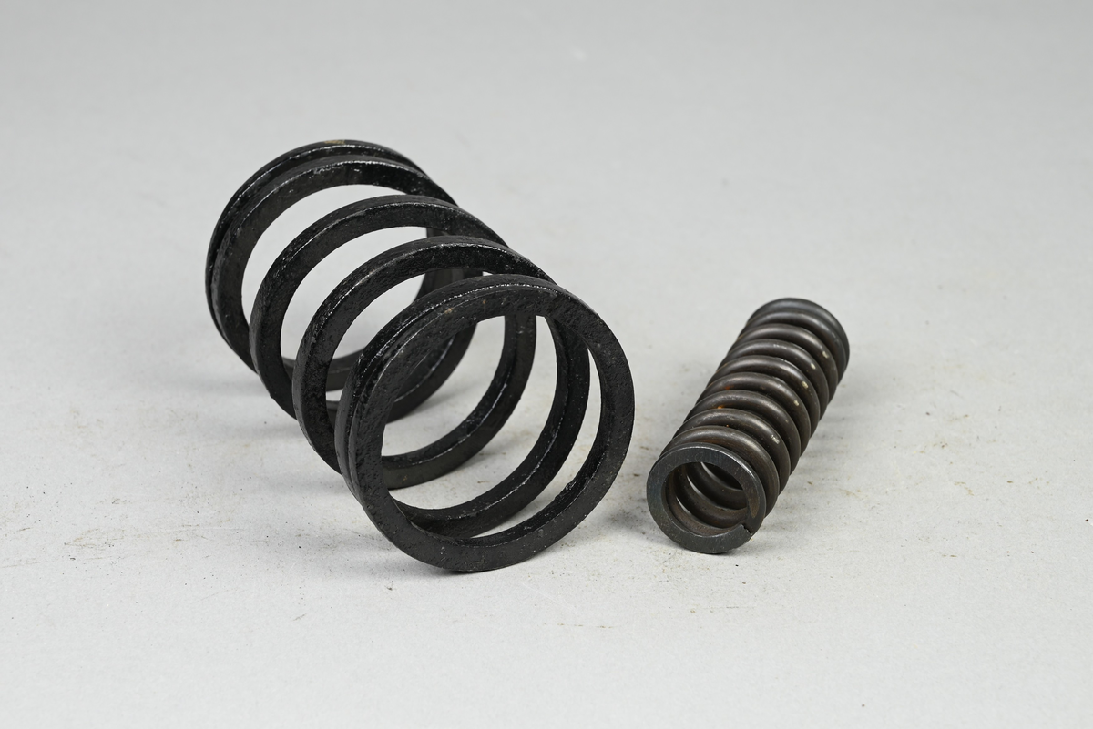 Två prov på diverse spiralfjädrar, svart. Tillverkad av A-B. Spiralfabriken. Tillhörande lapp med samma notering.
