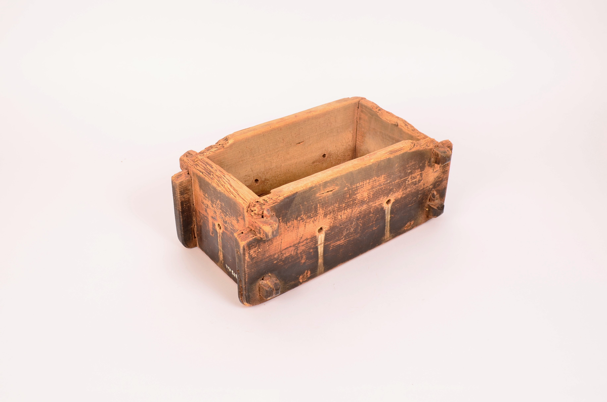 rektangulær kasseformat. Forma er av tre. Hull i botn og i sider. Veggene satt i hverandre ved hjelp av sine trepinner en oppe og en nede i hvert hjørne. forma er svært nedslitt på kantene. Totrepinner i satt på tvers under, før å holde botnen.