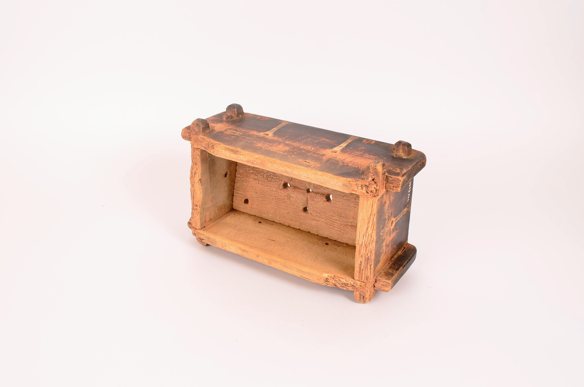 rektangulær kasseformat. Forma er av tre. Hull i botn og i sider. Veggene satt i hverandre ved hjelp av sine trepinner en oppe og en nede i hvert hjørne. forma er svært nedslitt på kantene. Totrepinner i satt på tvers under, før å holde botnen.