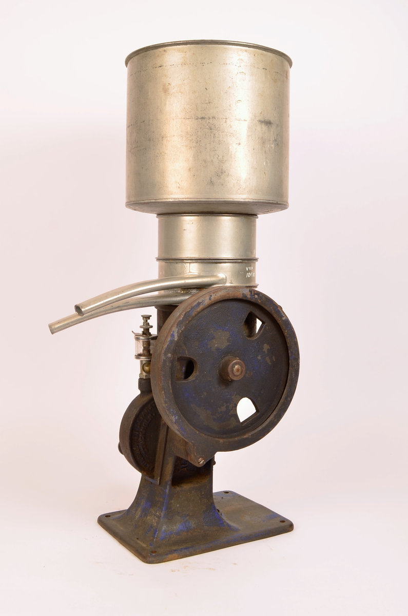 Manuelt drevet melkeseparator bestående av en solid undersel i støpejern montert på rektangulær fotplate med festehull. Underkonstruksjonen rommer det mekaniske systemet og er utstyr med sveiv med trehåndtak for hånddrift. På siden er et stort svinghjul synlig, delvis innkapslet i støpejernshus.
Øvre del består av en synlidrisk metallbeholder for påfylling av melk, montert over separasjonsenheten. Fra den øvre delen går to buende metallrør som leder henholdsvis fløte og skummelt melk ut i separate beholdere. Til separatoren følger løse deler, blant annet lokk og verktøy (nøkkel), som hærer til justering og vedlikehold.
På håndtaket er det utstøpt "60revprmin"