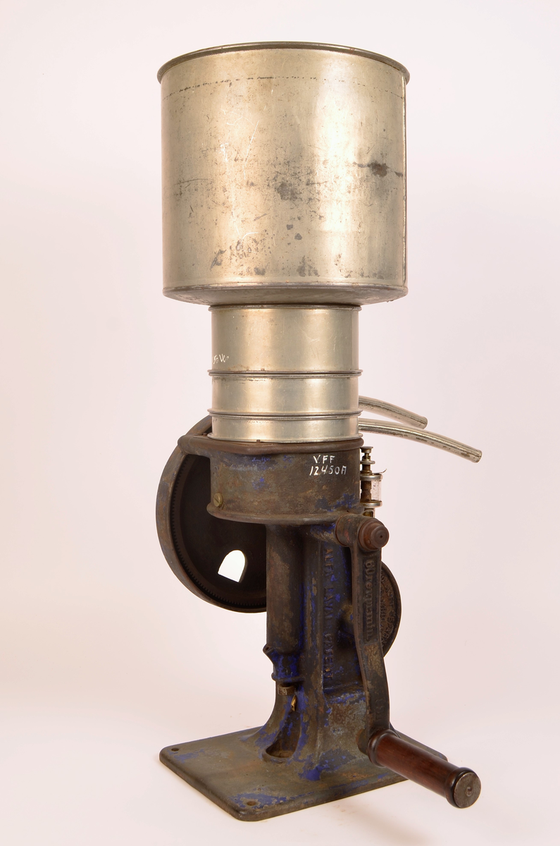 Manuelt drevet melkeseparator bestående av en solid undersel i støpejern montert på rektangulær fotplate med festehull. Underkonstruksjonen rommer det mekaniske systemet og er utstyr med sveiv med trehåndtak for hånddrift. På siden er et stort svinghjul synlig, delvis innkapslet i støpejernshus.
Øvre del består av en synlidrisk metallbeholder for påfylling av melk, montert over separasjonsenheten. Fra den øvre delen går to buende metallrør som leder henholdsvis fløte og skummelt melk ut i separate beholdere. Til separatoren følger løse deler, blant annet lokk og verktøy (nøkkel), som hærer til justering og vedlikehold.
På håndtaket er det utstøpt "60revprmin"