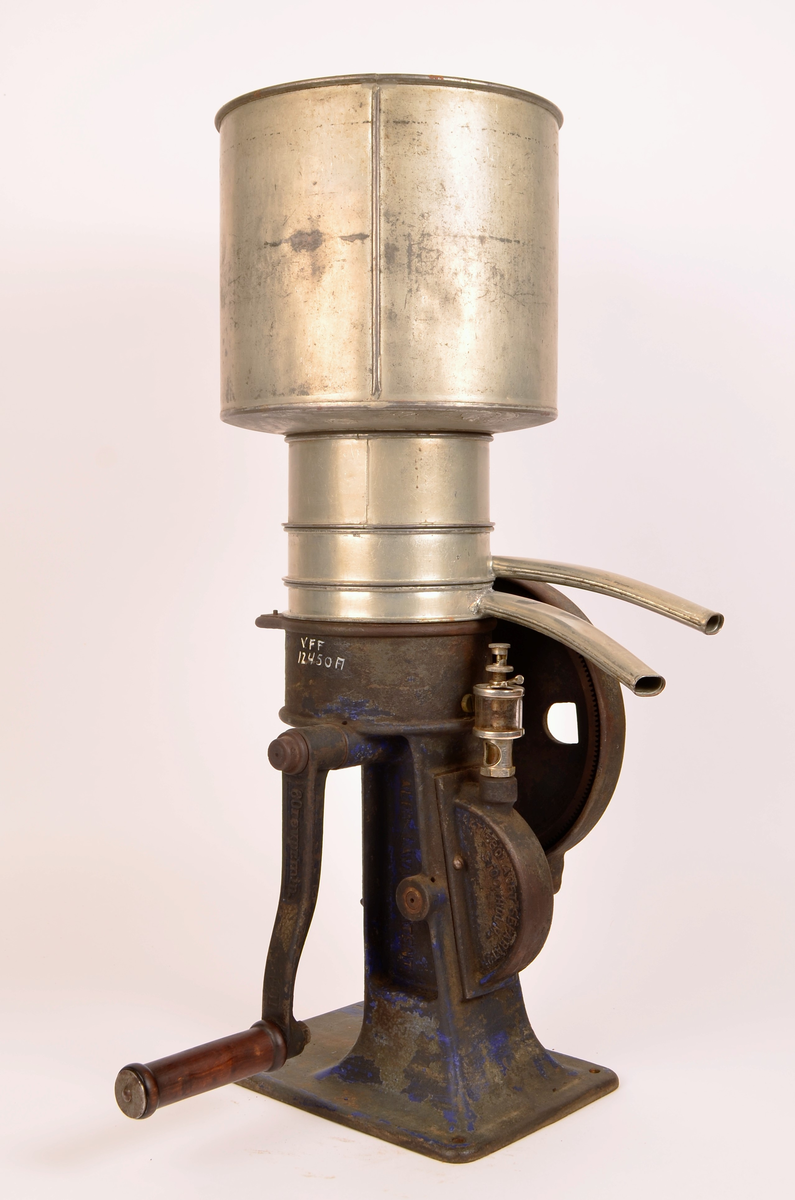 Manuelt drevet melkeseparator bestående av en solid undersel i støpejern montert på rektangulær fotplate med festehull. Underkonstruksjonen rommer det mekaniske systemet og er utstyr med sveiv med trehåndtak for hånddrift. På siden er et stort svinghjul synlig, delvis innkapslet i støpejernshus.
Øvre del består av en synlidrisk metallbeholder for påfylling av melk, montert over separasjonsenheten. Fra den øvre delen går to buende metallrør som leder henholdsvis fløte og skummelt melk ut i separate beholdere. Til separatoren følger løse deler, blant annet lokk og verktøy (nøkkel), som hærer til justering og vedlikehold.
På håndtaket er det utstøpt "60revprmin"