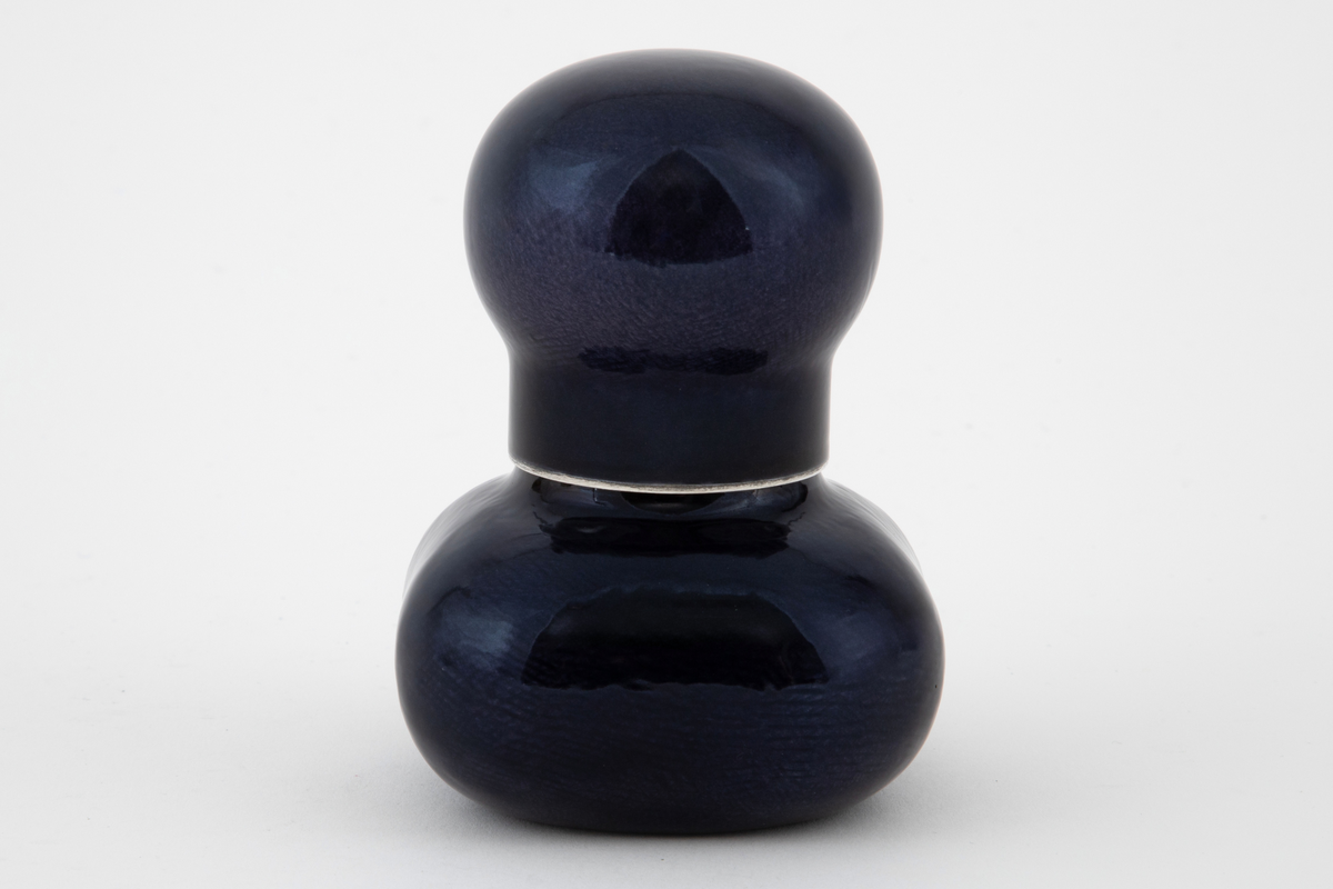 Krukke med lokk i sølv med pålagt emalje. Firekantet beholder med utbulede hjørner og sylindrisk hals. Tilnærmet kuleformet lokk med sylindrisk hals, som skyves ned over beholderens hals. Utvendig dekket med mørkeblå emalje på frest bunn.