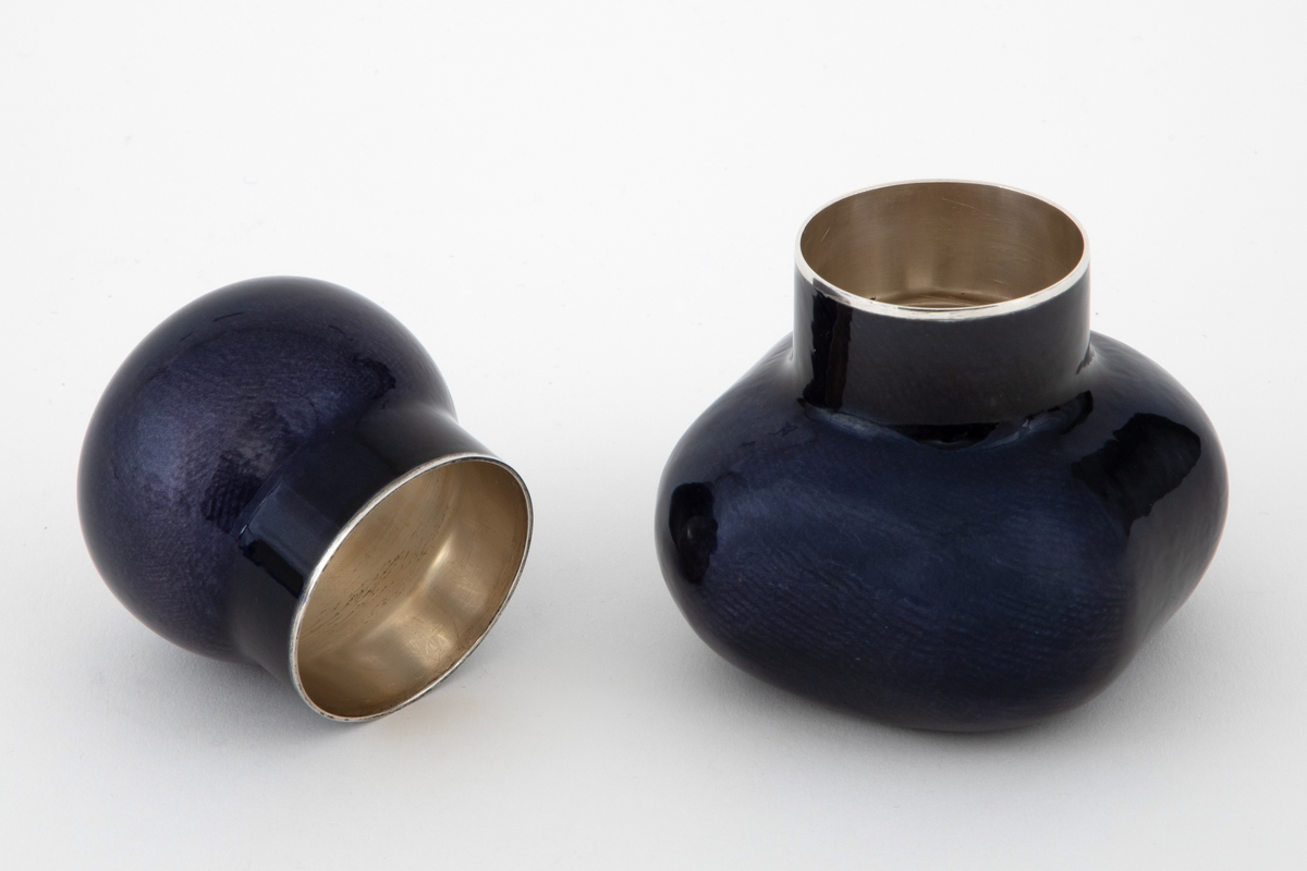 Krukke med lokk i sølv med pålagt emalje. Firekantet beholder med utbulede hjørner og sylindrisk hals. Tilnærmet kuleformet lokk med sylindrisk hals, som skyves ned over beholderens hals. Utvendig dekket med mørkeblå emalje på frest bunn.