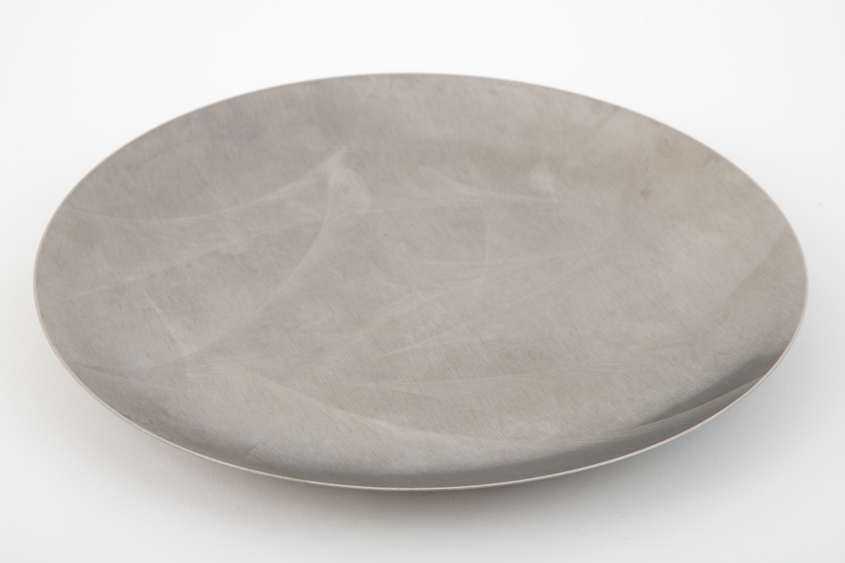 Sirkelrundt fat i stål med frest dekor på oversiden.