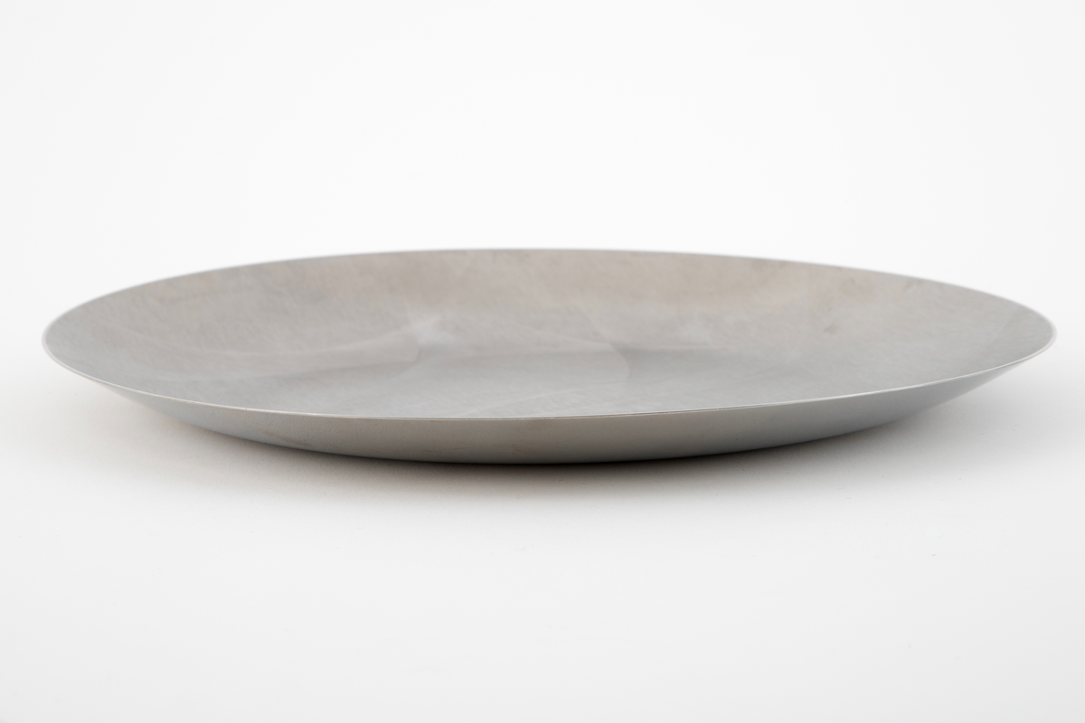 Sirkelrundt fat i stål med frest dekor på oversiden.