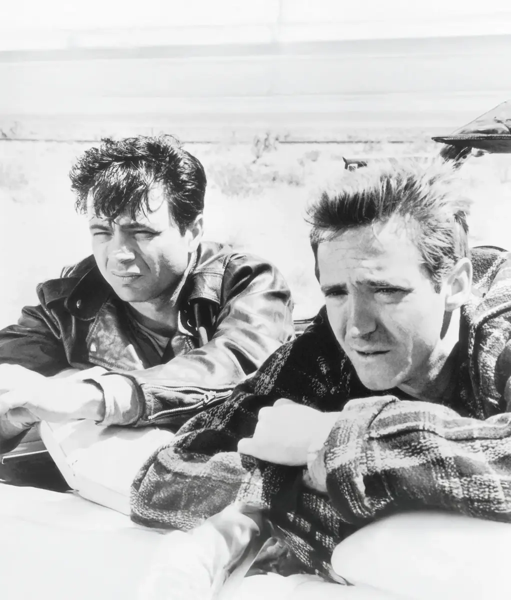 Två män med ett ökenlandskap i bakgrunden.