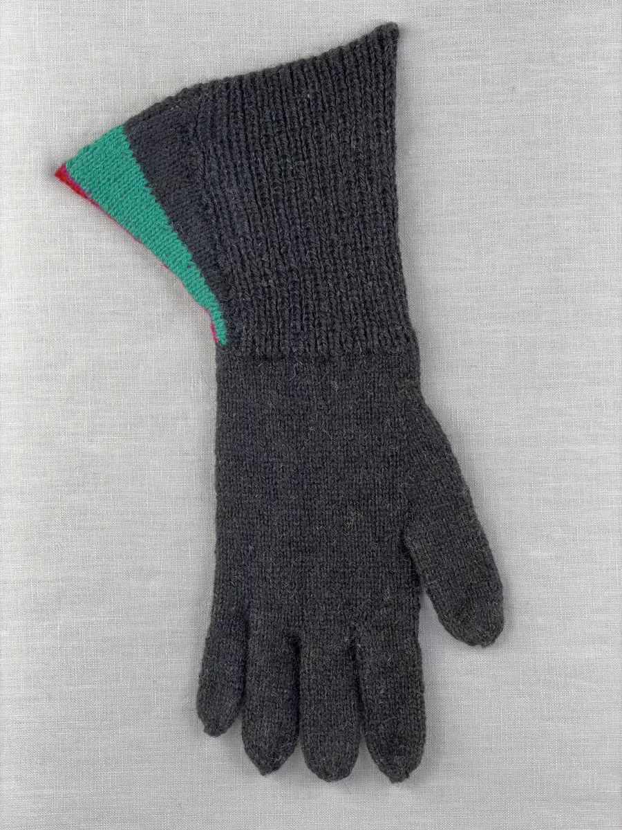 En stickad fingervante, med mudd/krage i 1-1 resår (1 rät och 1 avig maska) och delstickad kil i slätstickning samt vante i slätstickning, av 2-trådigt ullgarn. Vanten har stickad kiltumme och fingrarna har strålhoptagning i toppen.
