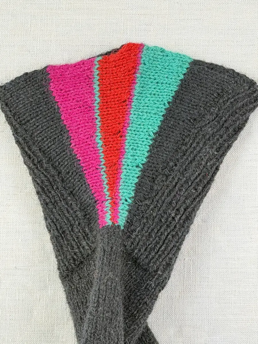 En stickad fingervante, med mudd/krage i 1-1 resår (1 rät och 1 avig maska) och delstickad kil i slätstickning samt vante i slätstickning, av 2-trådigt ullgarn. Vanten har stickad kiltumme och fingrarna har strålhoptagning i toppen.
