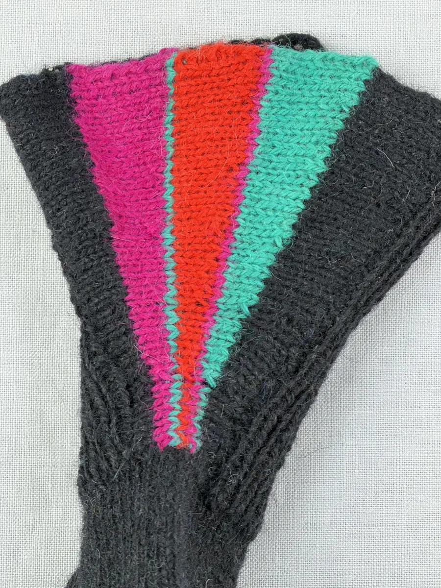 En stickad tumvante, med mudd/krage i 1-1 resår (1 rät och 1 avig maska) och delstickad kil i slätstickning samt vante i slätstickning, av 2-trådigt ullgarn. Vanten har stickad kiltumme och bandhoptagning i toppen.
