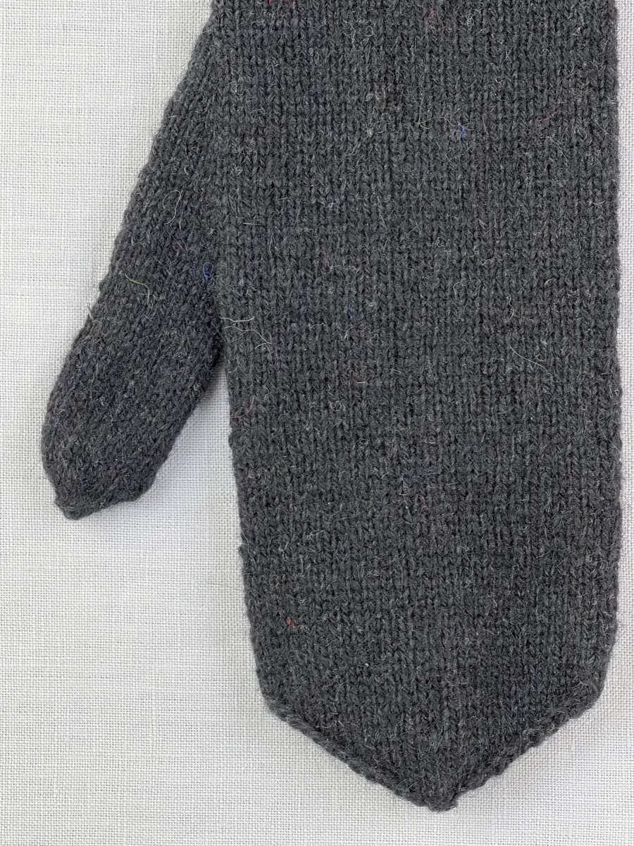 En stickad tumvante, med mudd/krage i 1-1 resår (1 rät och 1 avig maska) och delstickad kil i slätstickning samt vante i slätstickning, av 2-trådigt ullgarn. Vanten har stickad kiltumme och bandhoptagning i toppen.
