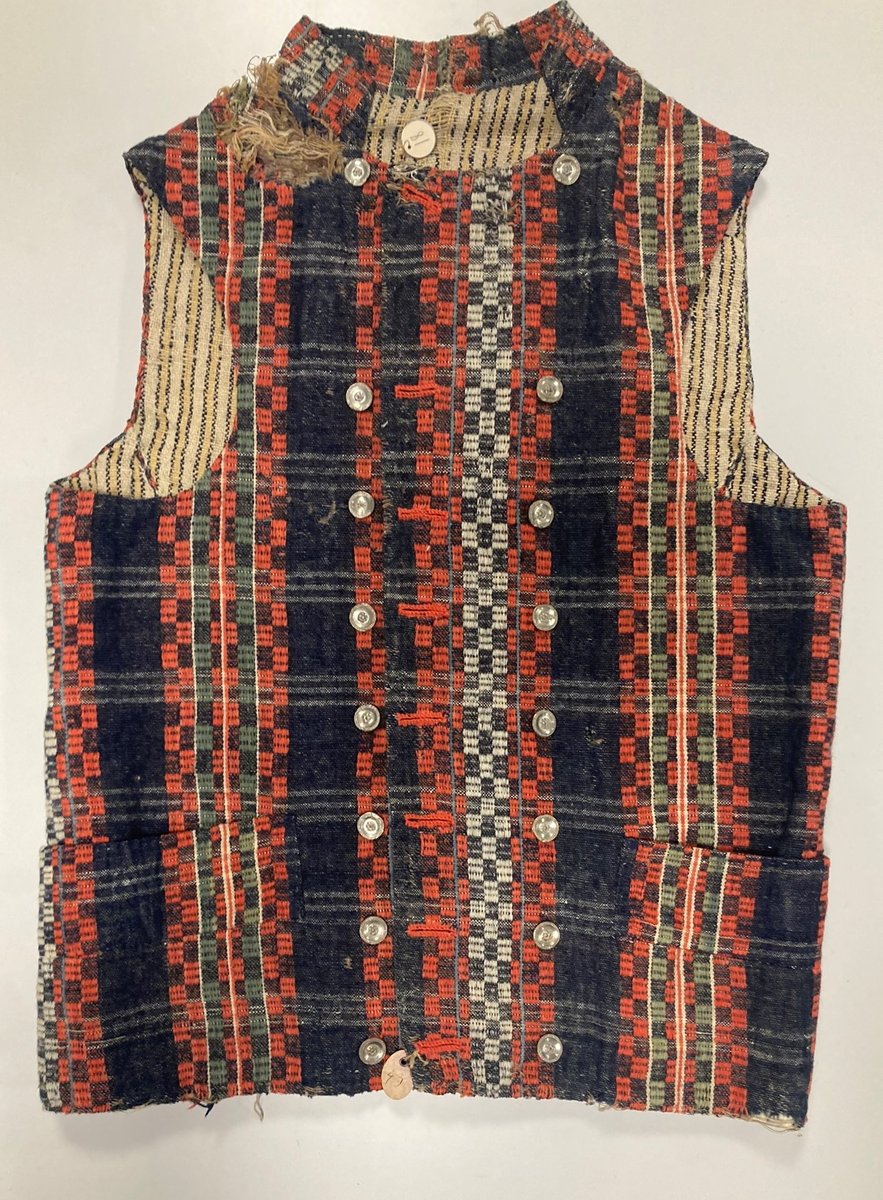 Ullvest med krage til mann i blått, grønt, rødt og hvitt. Dobbeltspent med tinnknapper. Foret med linstoff med gule/blå striper.