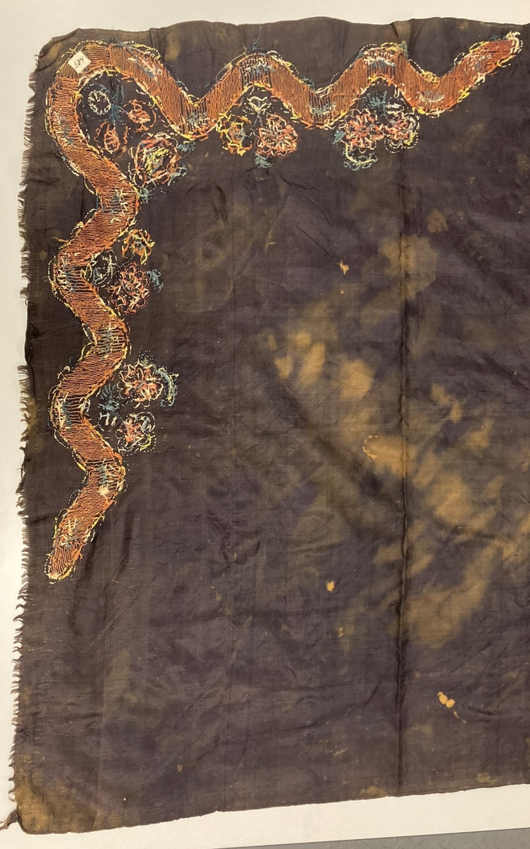 Kvadratisk svart silketørkle. Brodert blomsterdekor i et hjørne. Falmet og blekeflekker, en frynset kant.