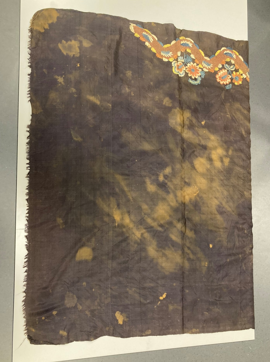 Kvadratisk svart silketørkle. Brodert blomsterdekor i et hjørne. Falmet og blekeflekker, en frynset kant.