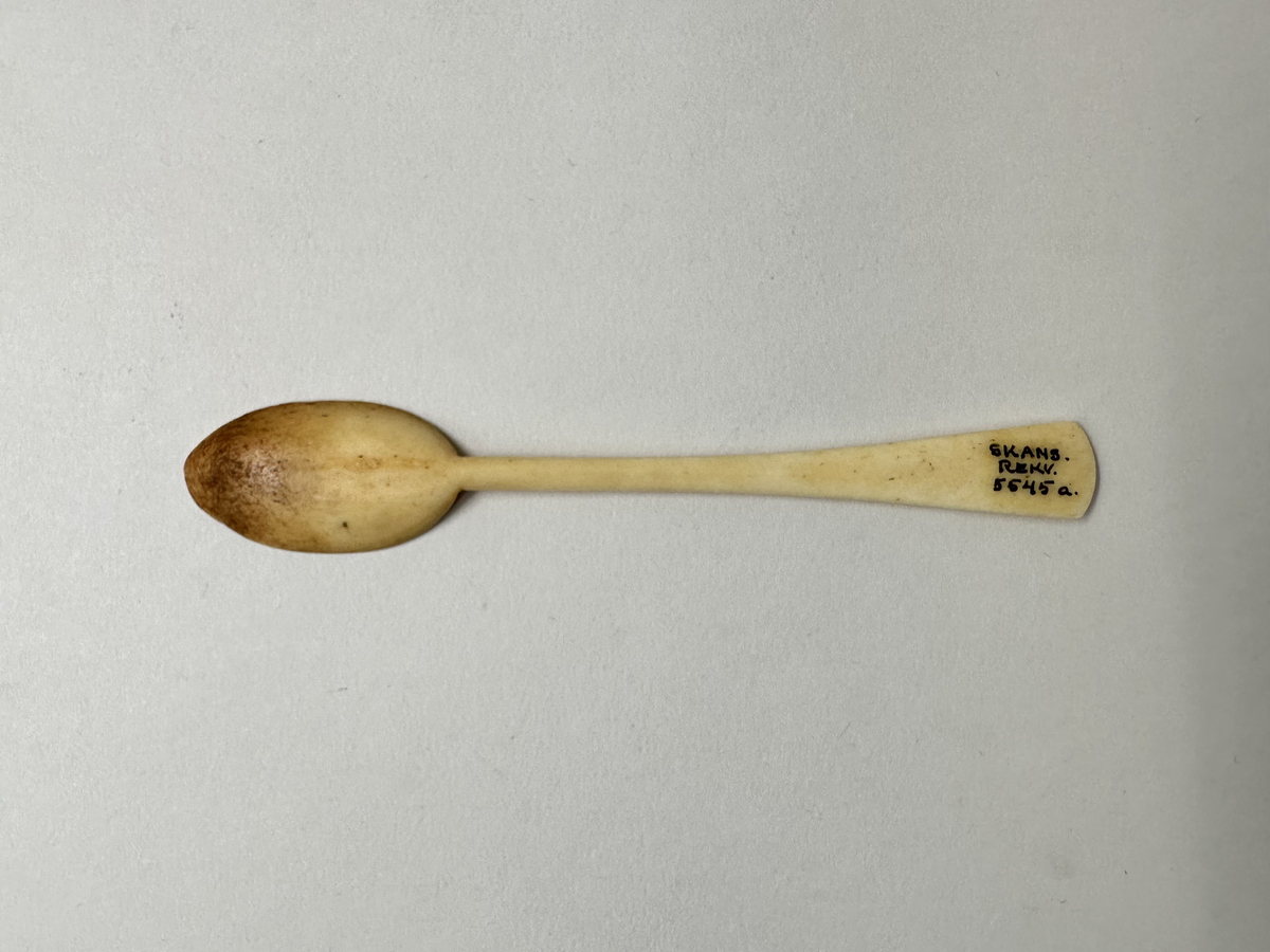 Äggsked av ben. Droppformat grunt blad, skaftet platt och utsväng mot änden, konvext skuret avslut. Missfärgat blad. 