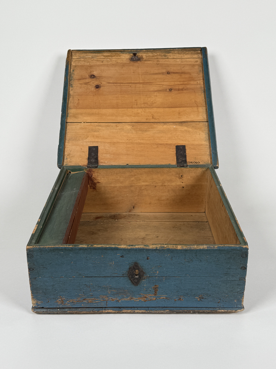 Skrin av furu med sinkade hörn och underifrån itappad botten. Gångjärn, låshake och nyckelskylt. Lås saknas (har varit utanpåliggande). Läddika med lock. Målat utvändigt med stiliserad blomsterdekor i gult, rött och svart mot heltäckande blå botten. 