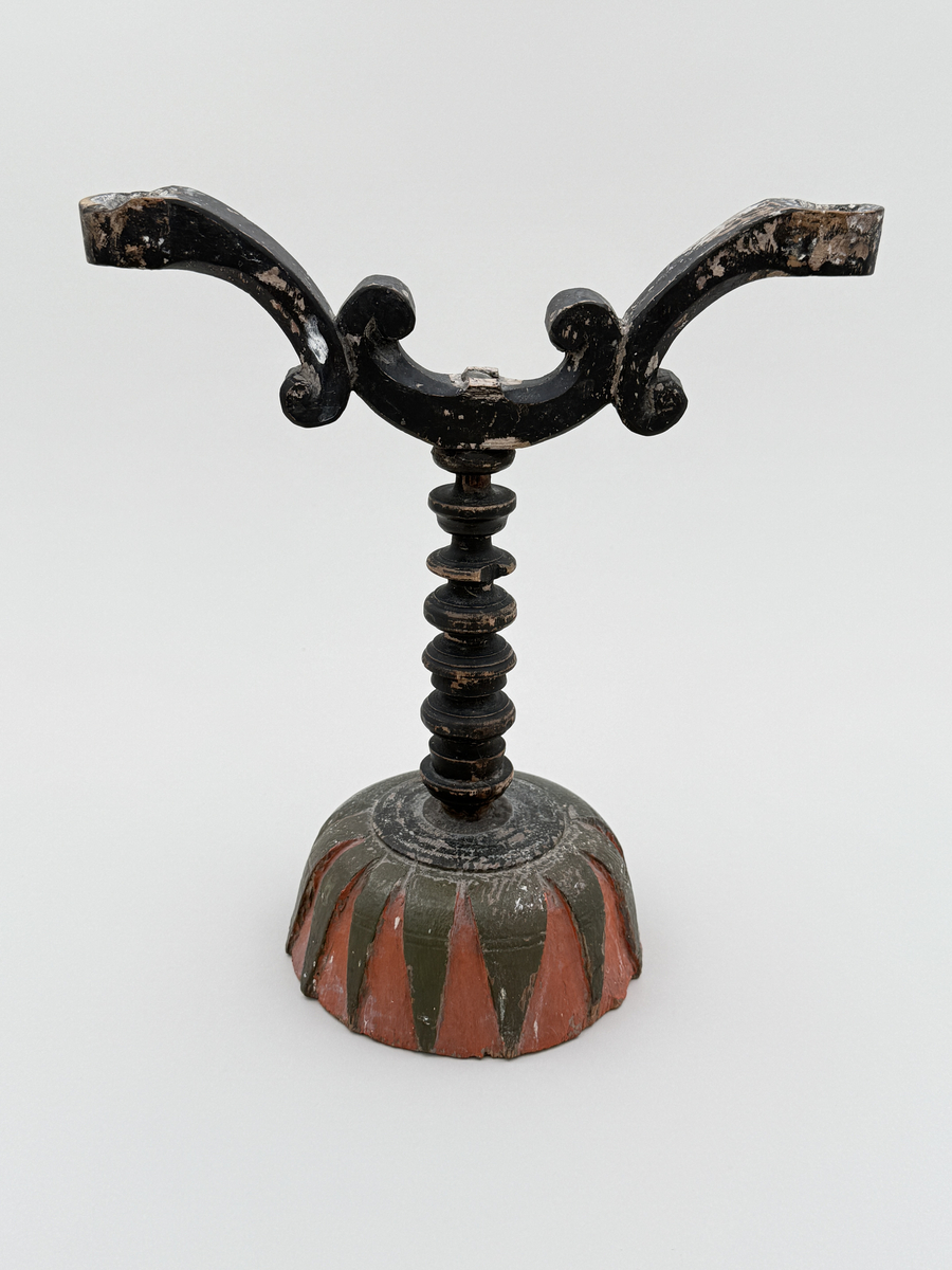 Av trä, svarvad och skuren, tvåarmad, målad i svart, rött och grönt.


Julljusstake. Enligt uppgift skuren av en soldat. Ommålad i en senare tid.