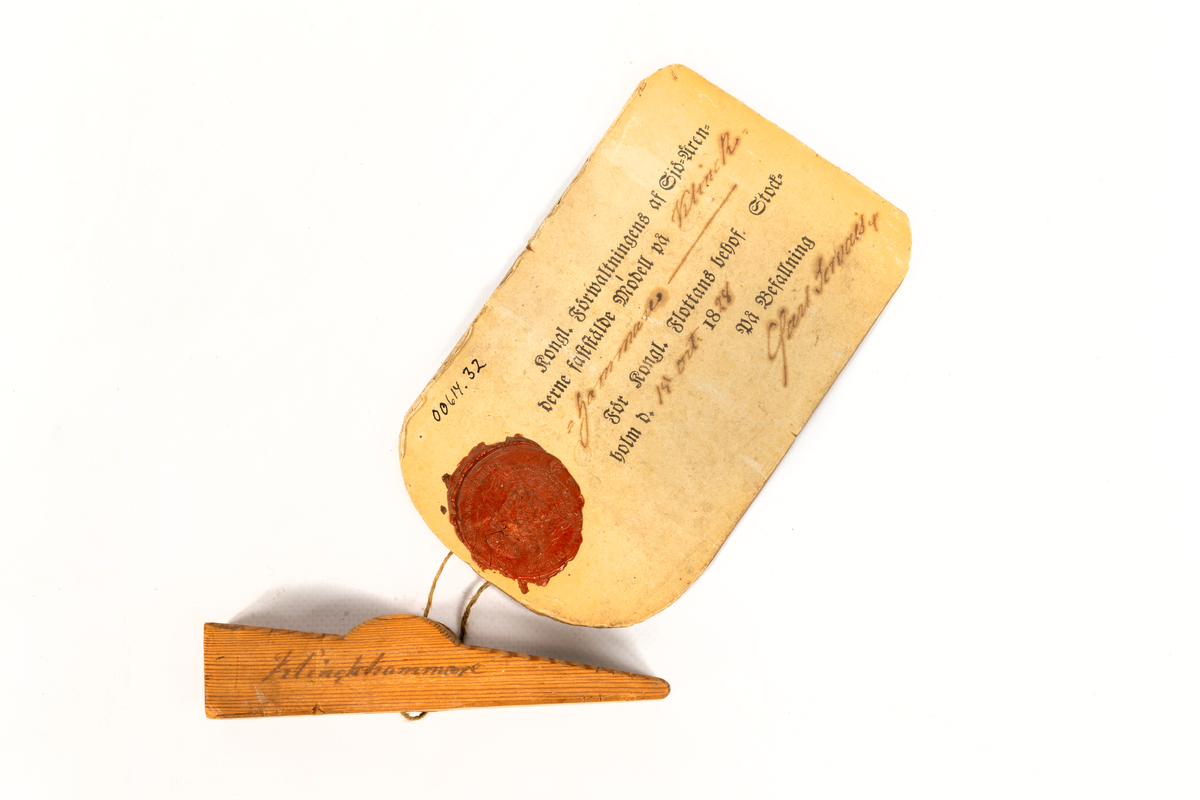 Modell i trä av klinkhammare. Vidhäftad etikett med sigill och texten "Kongl. Förwaltningens af Sjö-ärenderne faststälde modell på Pynt-Hammare. För Kongl. Flottans behof. Stockholm d. 19 oct. 1828. På befallning Carl Servais"