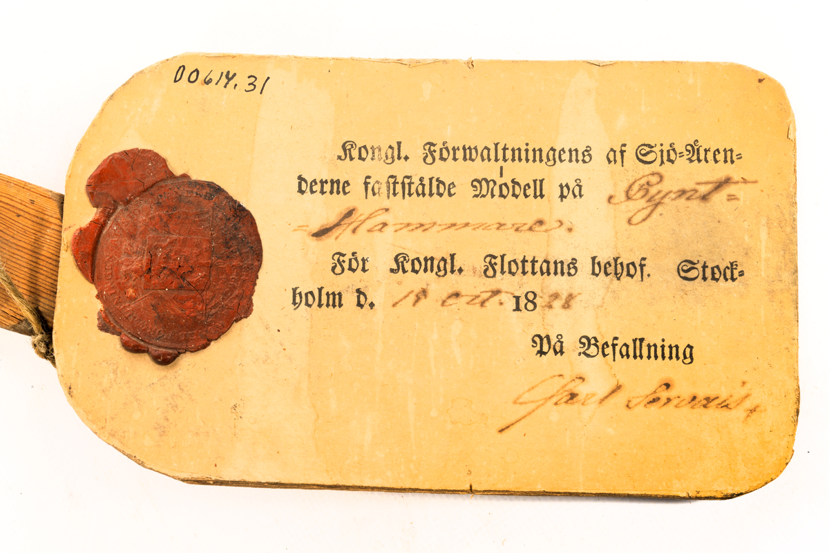 Modell i trä av pynthammare. Vidhäftad etikett med sigill och texten "Kongl. Förwaltningens af Sjö-ärenderne faststälde modell på Pynt-Hammare. För Kongl. Flottans behof. Stockholm d. 19 oct. 1828. På befallning Carl Servais"
