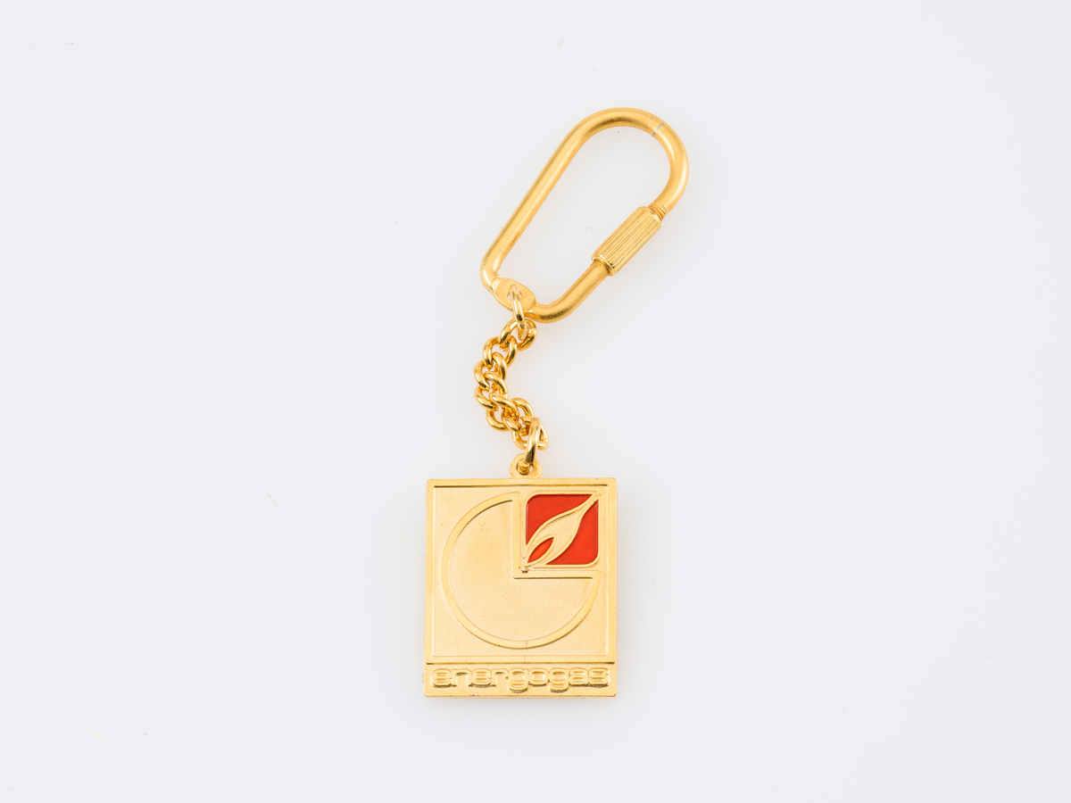 Nøkkelring med Energogas sin logo og serbisk tekst som informerer om "30 år med gassvirksomhet". Nøkkelringen er oppbevart i orginal emballasje.