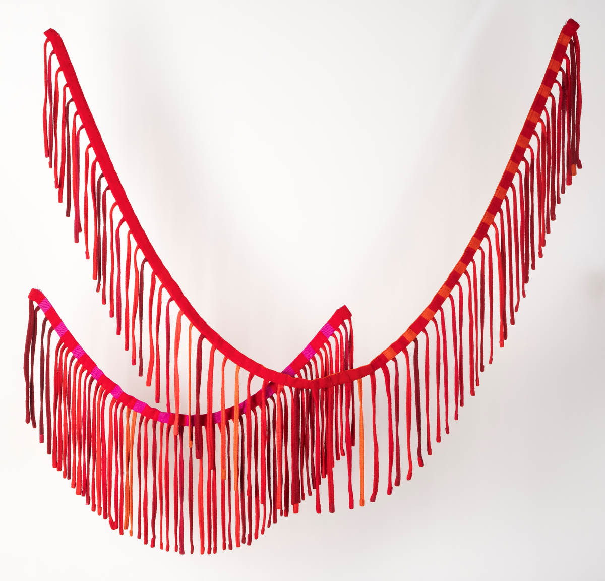 Tekstilskulptur i gobelinvev. Verket består av to lange vevde bånd. Fra disse båndene henger det ned lange, smale bånd. Materialene er kraftig, ufarget lingarn i renningen og kunstvevgarn, åklegarn og ryegarn i innslaget. Fargene på båndene er i en rødskala fra rødlilla, kald rød, varm rød til oransje.