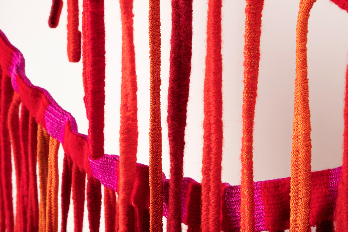 Tekstilskulptur i gobelinvev. Verket består av to lange vevde bånd. Fra disse båndene henger det ned lange, smale bånd. Materialene er kraftig, ufarget lingarn i renningen og kunstvevgarn, åklegarn og ryegarn i innslaget. Fargene på båndene er i en rødskala fra rødlilla, kald rød, varm rød til oransje.