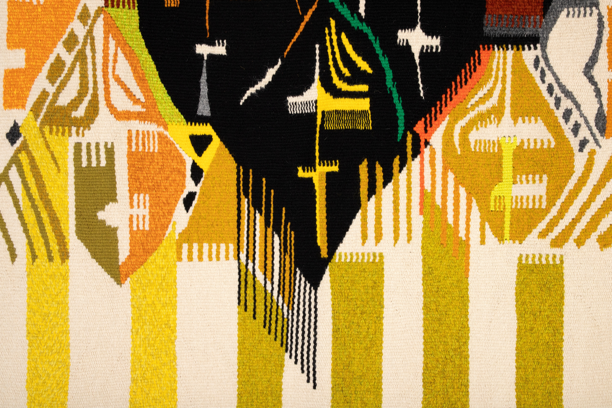 Rektangulært billedvev med naturhvit bunn. Øverste del danner et fratrukket sceneteppe med masker som stikker frem. Svarte masker i midten danner en rombeform. Masker i forskjellige gul-, grønn- og oransjetoner på siden av disse. Nedre del av veven har vertikale striper i gult og grønt. Sidefrynser på begge sider.