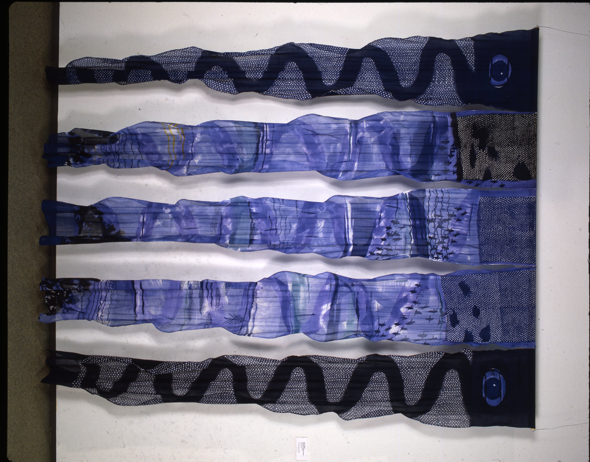 Rektangulært billedvev med naturhvit bunn. Øverste del danner et fratrukket sceneteppe med masker som stikker frem. Svarte masker i midten danner en rombeform. Masker i forskjellige gul-, grønn- og oransjetoner på siden av disse. Nedre del av veven har vertikale striper i gult og grønt. Sidefrynser på begge sider.