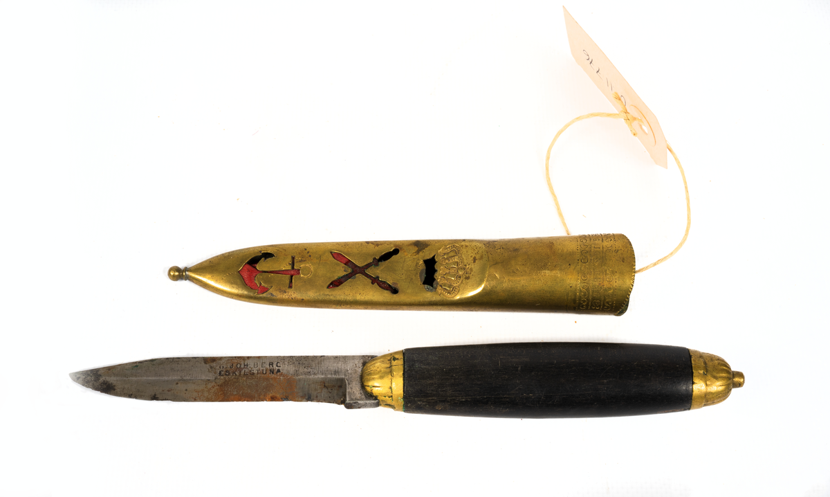 Kniv med svartlackerat träskaft och balja av mässing. Baljan har dekor av en krona, korsande vapen och ett ankare. Insidan av baljan är klädd med läder.

Tillverkarens namn är märkt på både blad och balja.