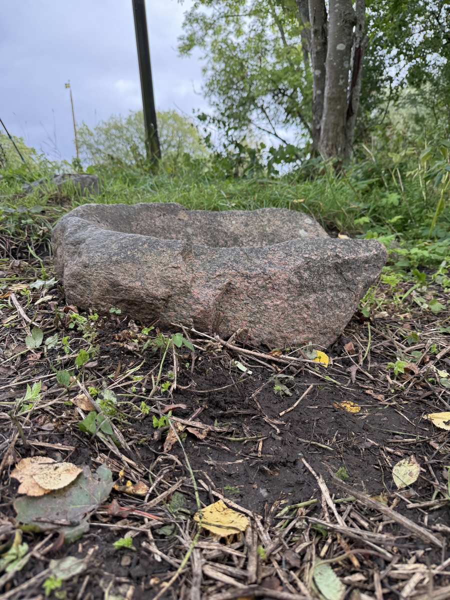 Sten urholkad till följd av nötning. Skålad, kanten lägre åt ena sidan. 