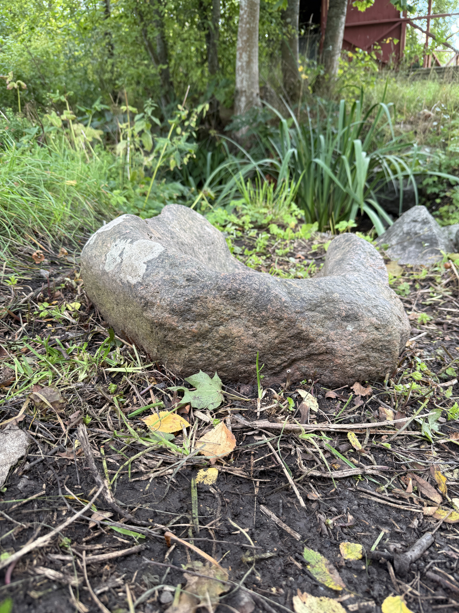 Sten urholkad till följd av nötning. Skålad, kanten lägre åt ena sidan. 