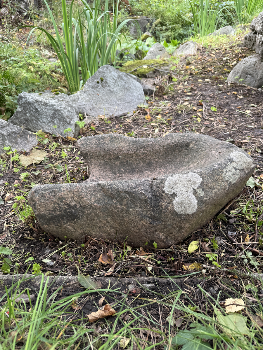 Sten urholkad till följd av nötning. Skålad, kanten lägre åt ena sidan. 