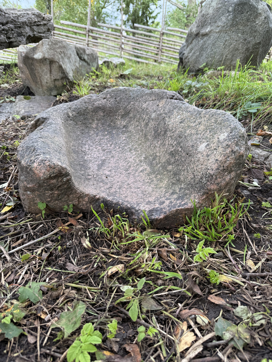 Sten urholkad till följd av nötning. Skålad, kanten lägre åt ena sidan. 