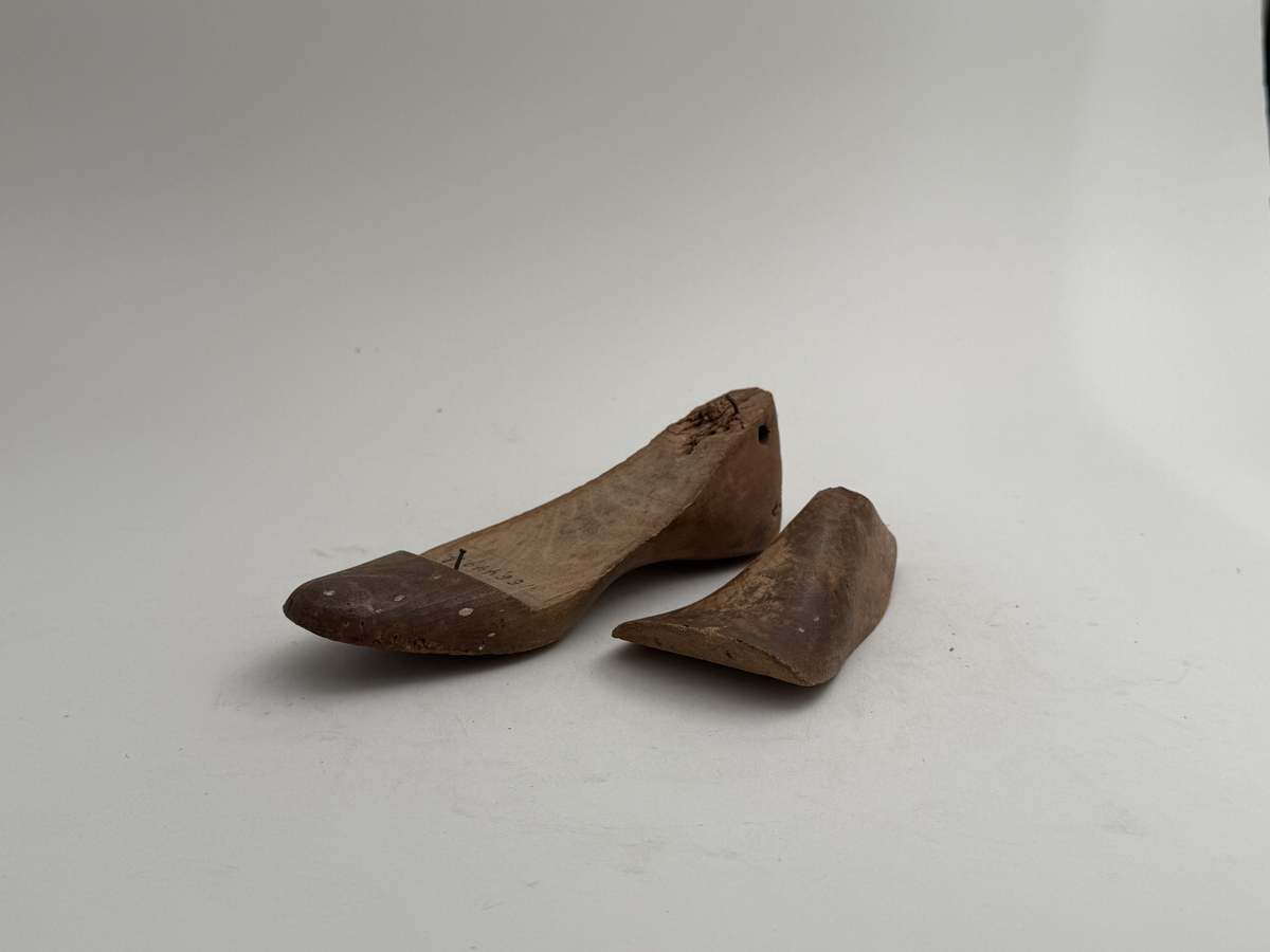 Skoläst, för högerfot, av bok. Överdelen lös. Hål för upphängning genom hälen.
 