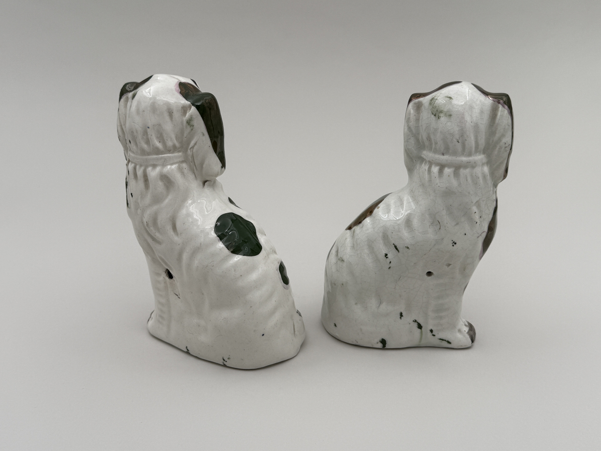 Figuriner av porslin i form av sittande hundar, glaserade, med överglasymålad dekor och förgyllning.  