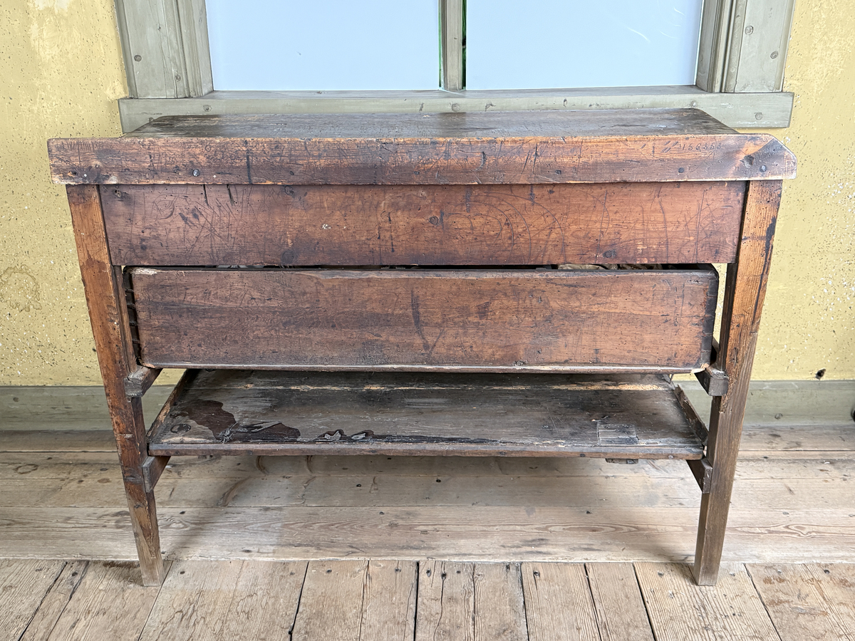 Avlastningsbord med rektangulär form, bemålad i beige-gult. Trågkant i skivans bakre kant. Övre lådvarvet med tre lådor, det undre lådvarvet med en låda. Längst ner en hylla. Dragknoppar av mässing, några saknas.