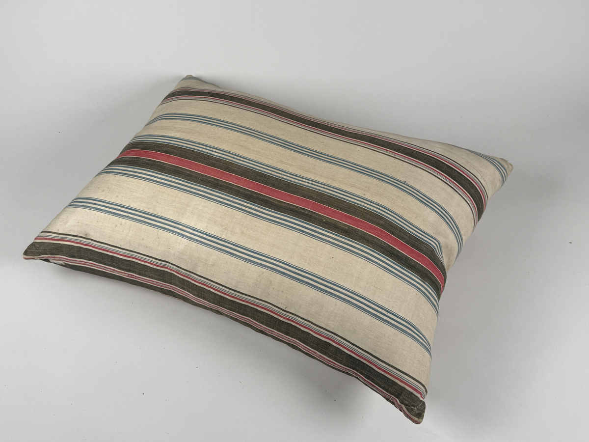 Rektangulär kudde av kypertvävd bomull, randig i svart, blått och rött. Förstärkta hörn. Stoppad med dun. Enstaka smärre lagningar. 