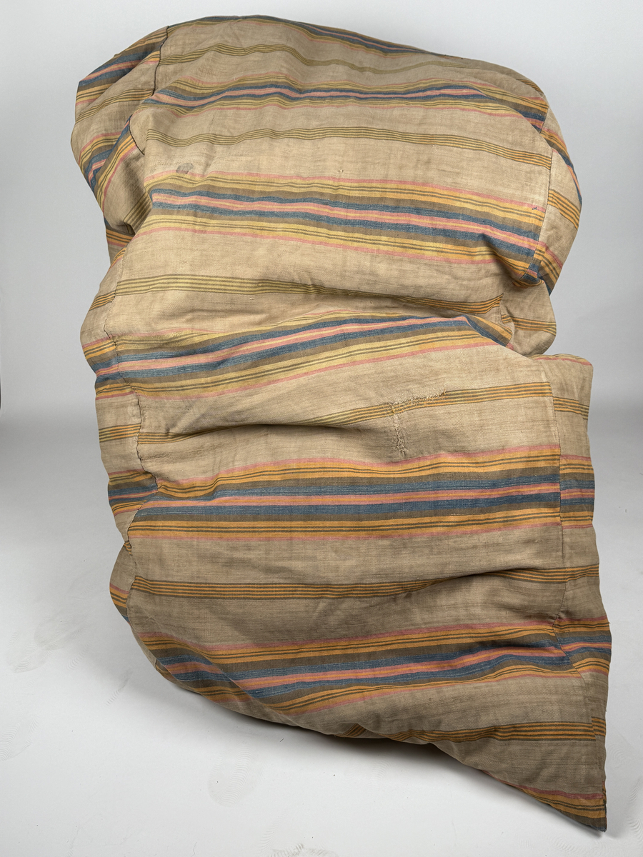 Soppat bolster av kypertvävd bomull, randigt i blått, gult, rött och brunt mot oblekt. Lagningar. 