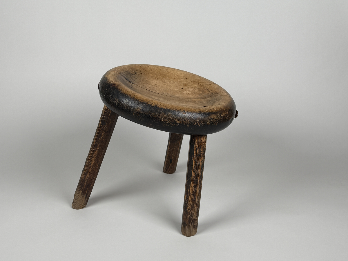 Pall med skålad sits av björk, åttkantiga ben av furu. Benen med ojämn längd så pallen lutar. Sitsen sprucken samt lagad med läderbitar och nubb. 