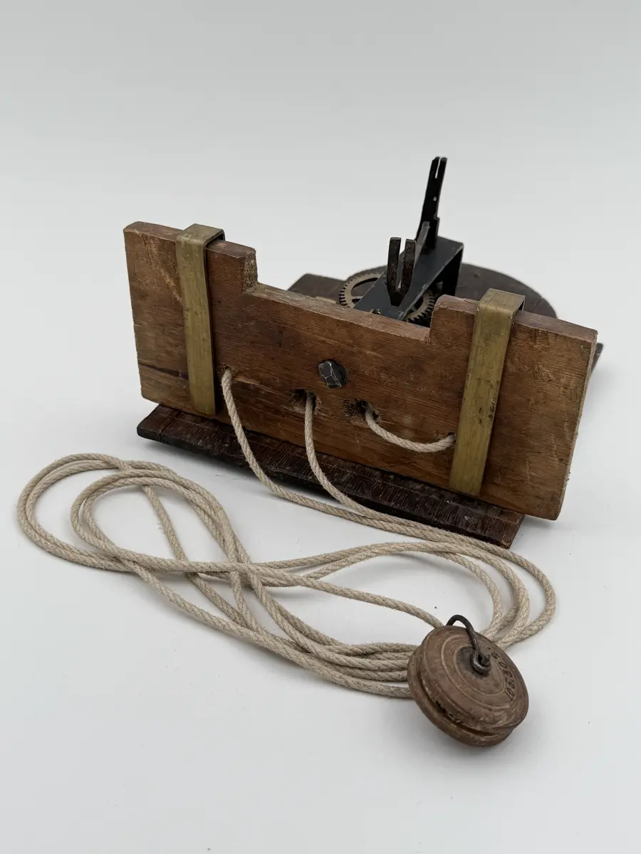 Förgylld med pastellagedekor (skadad), urtavla av bly med romerska siffror, visare av mässing, rund disk av bly ovan urtavlan. Urverket med kuggar av mässing, bottenplatta av buru som hålls p plats av mässingsbeslag. Snöre löper ner från urverket med en trissa i änden. 