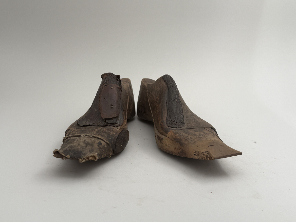 Skoläst för herrskor.
Gjorda i björkträ med läderbitar fastpliggade på vristdelen. Höger tåhäll klädd med lärft. 