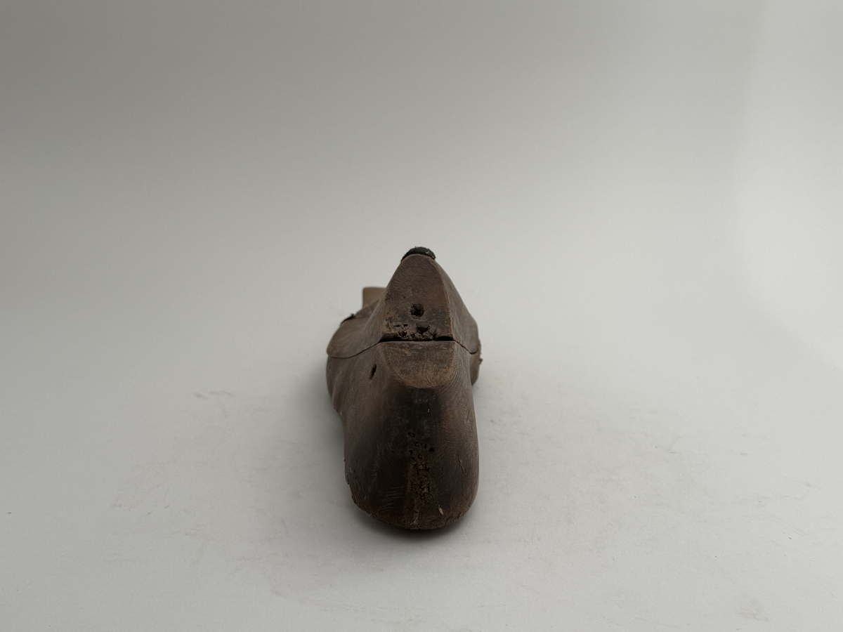 Skoläst för herrskor. Vänsterfot.
Gjord i björkträ med läderbitar fastpliggade på vristdelen. 
 